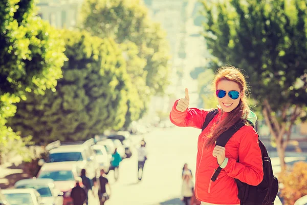 Smiling woman with sunglasses and backpack in San Francisco city on sunny day — Stock Photo, Image
