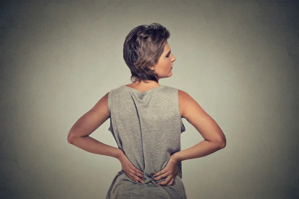 Mujer joven de pie con dolor de espalda — Foto de Stock