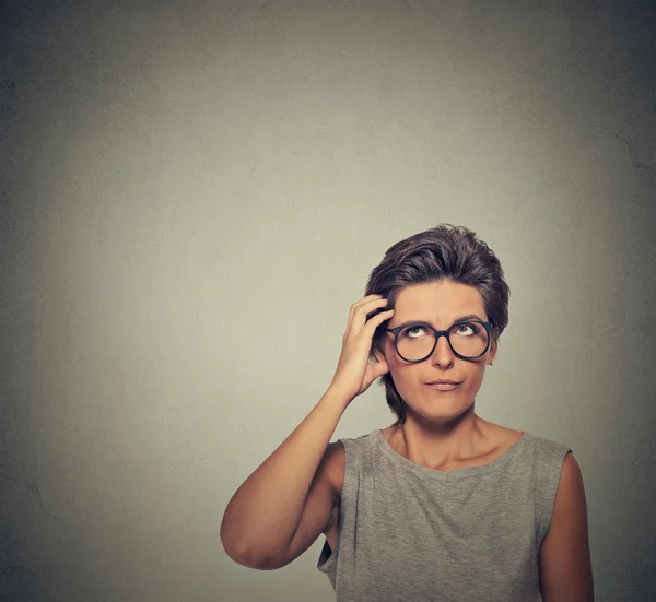 Confused thinking woman in glasses bewildered scratching her head — Zdjęcie stockowe