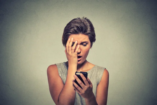 Stressed woman holding cellphone disgusted shocked with message she received — Stockfoto