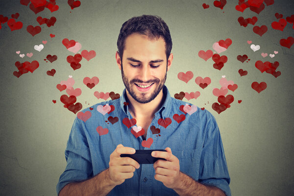 мужчина отправляет любовные смс на мобильный телефон с разлетающимися сердцами
