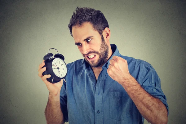 Angry young man screaming at alarm clock, running late — Stock Photo, Image