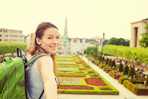 Happy woman in Brussels downtown extending you arm inviting to visit Mont des Arts garden — Stock Photo, Image
