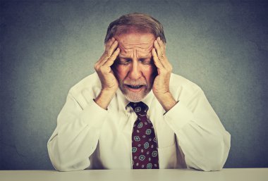 Stressed hopeless elderly business man in depression sitting at the office table 