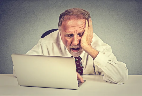 Hombre mayor cansado y soñoliento sentado en su escritorio frente a la computadora portátil —  Fotos de Stock