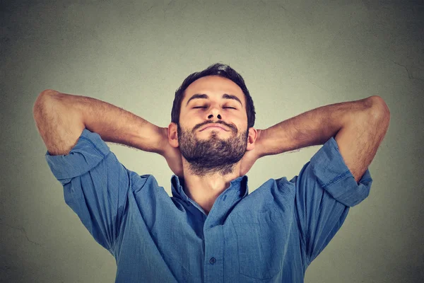 Gelukkig jonge man in blauw shirt op zoek naar boven in gedachte ontspannen of slapen — Stockfoto