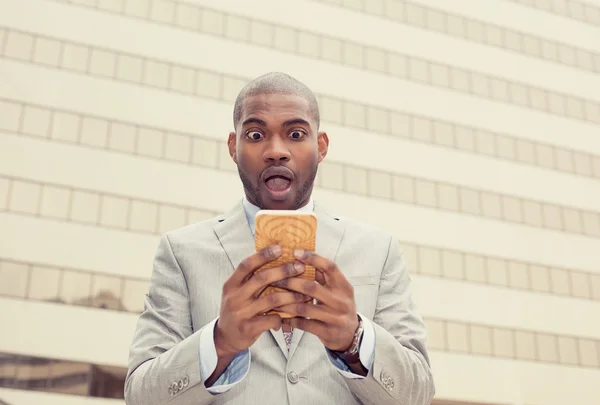 Shocked young business man looking at phone seeing bad news — Stock Photo, Image