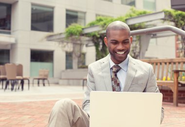 happy businessman working on laptop computer outdoors