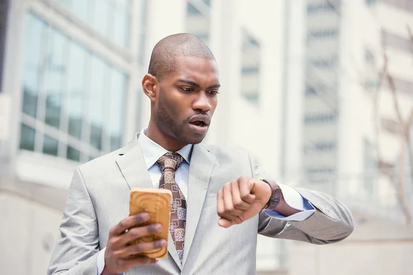 Stressed business man looking at wrist watch, running late for meeting outside corporate office — Stockfoto