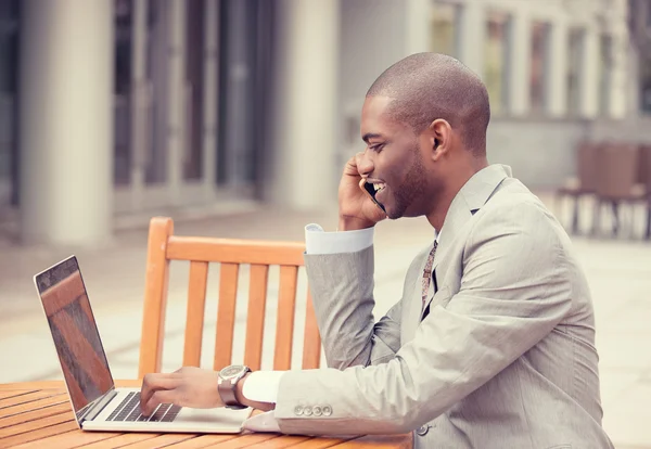 Schöner junger Geschäftsmann arbeitet draußen mit Laptop und telefoniert mit dem Handy — Stockfoto