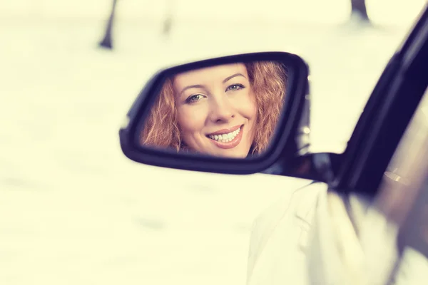 Reflejo de conductor mujer feliz en el espejo retrovisor lateral del coche. Viaje seguro de invierno, concepto de conducción de viaje — Foto de Stock
