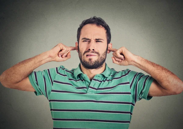 Headshot displeased man plugging ears with fingers doesn't want to listen — ストック写真