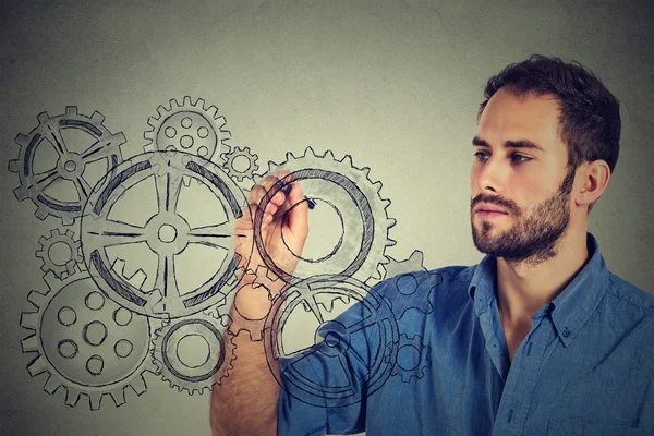 Gears and ideas creativity concept. Young man drawing gears with pen — Stockfoto
