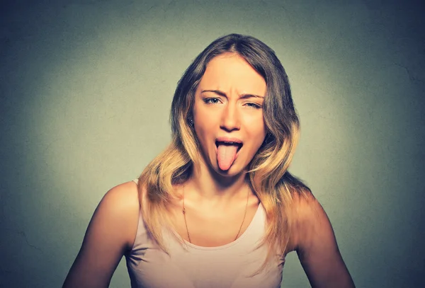 Funny woman showing her tongue isolated on gray wall background — Stock Photo, Image