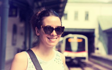 young woman standing on subway platform waiting approaching train 