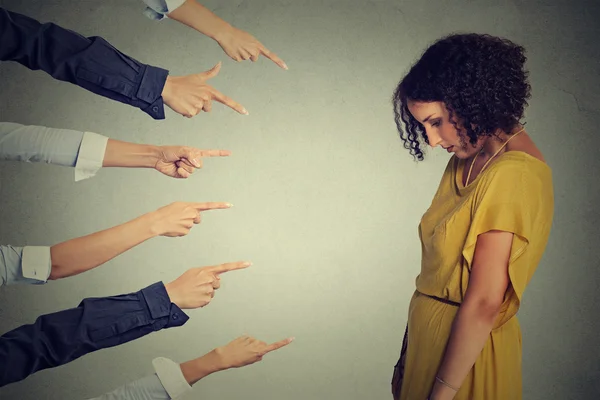 Acusación de culpable. Triste mujer molesta mirando hacia abajo muchos dedos apuntando a su espalda — Foto de Stock