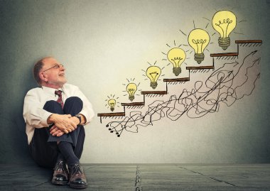 happy elderly executive man relaxed sitting on a floor in his office looking up