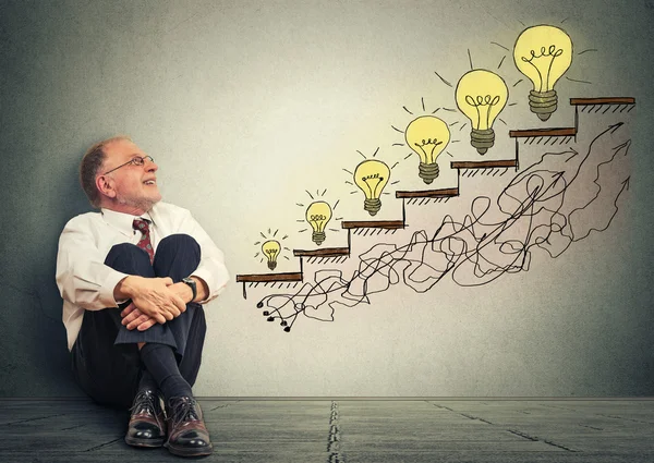 Happy elderly executive man relaxed sitting on a floor in his office looking up — Stok fotoğraf