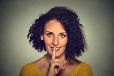 happy young woman placing finger on lips asking shhhhh, quiet, silence
