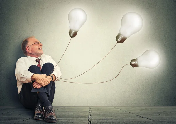 Joyful senior man holding three light bulbs having many idea — 스톡 사진