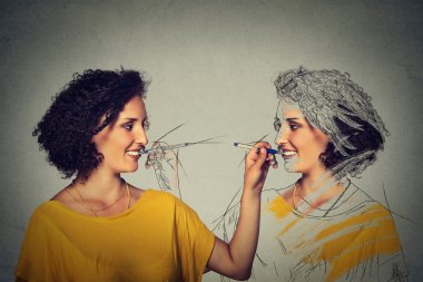 Attractive young woman drawing a picture portrait sketch of herself 