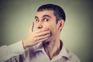 Headshot of a scared adult man with hand covering his mouth 