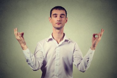 Young man meditating isolated on gray wall background 
