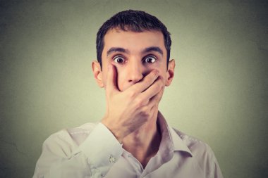 scared young man with hand over his mouth, stunned and speechless