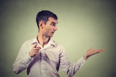 young man looking to side while pointing at you camera, surprised