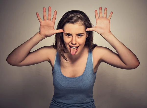 Woman with funny face mocking someone sticking her tongue out — Stock fotografie