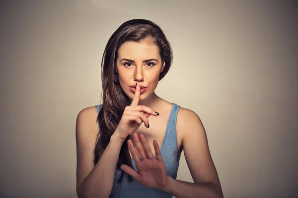 Porträt einer jungen schönen Frau mit dem Finger auf den Lippen isoliert auf grauem Wandhintergrund — Stockfoto