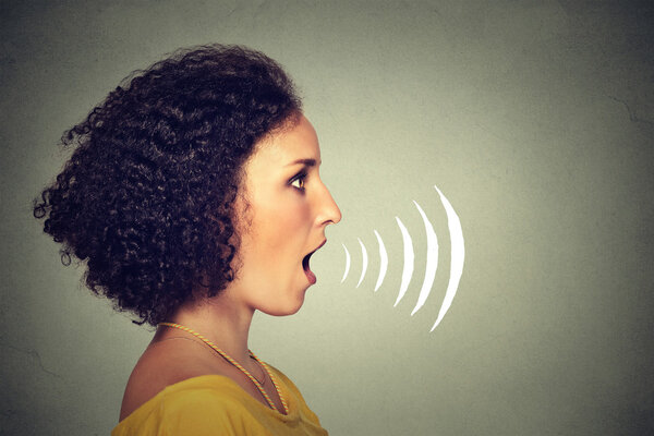Side profile young woman talking with sound waves coming out of her mouth 