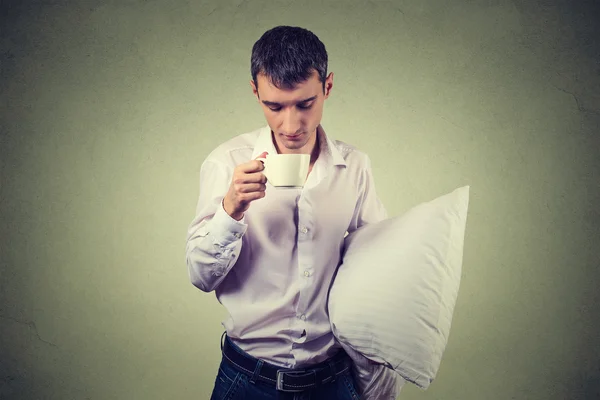 Very tired, almost falling asleep business man holding a cup of coffee and pillow — Stock Photo, Image