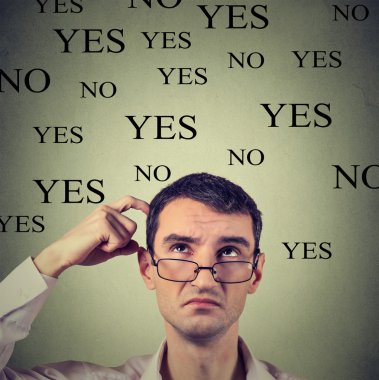 Headshot thinking perplexed young man in glasses with yes or no choice looking up