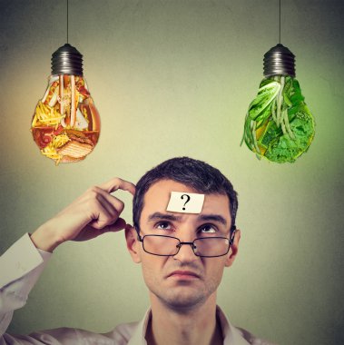 Man with question mark thinking looking up at junk food and vegetables shaped as light bulb