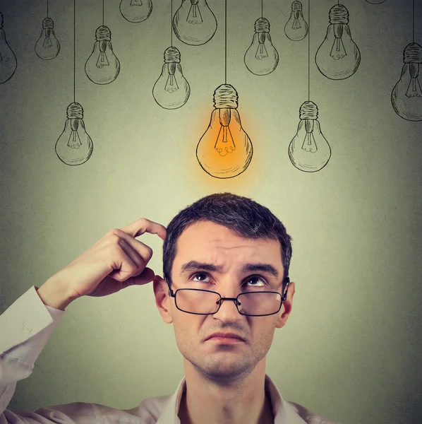 Portrait thinking man in glasses looking up with light idea bulb above head — 스톡 사진