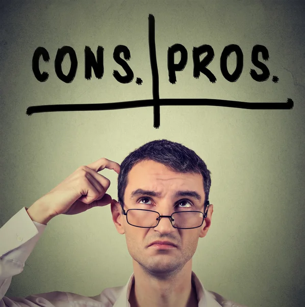 Pros and cons, for and against argument concept. Man with glasses looking up deciding — ストック写真