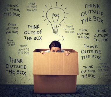 Think outside the box concept. Scared young woman sitting inside box