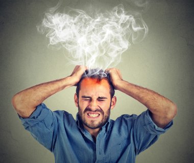 Stressed man having headache steam coming up isolated on gray wall background