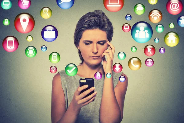 Confused woman using smartphone application icons flying out of cellphone — ストック写真