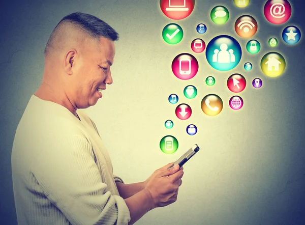 Happy man using texting on smartphone social media application icons flying up — 图库照片