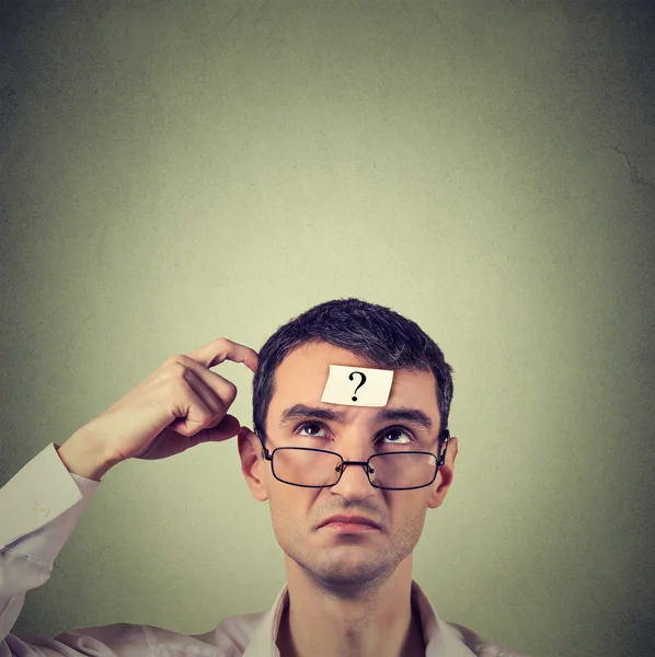 Thinking man with question mark isolated on gray wall background — Stockfoto