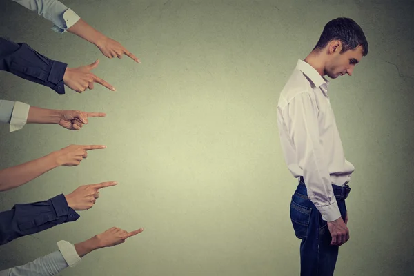 Accusation guilty person guy. Side profile sad upset man looking down many fingers pointing at him — Stockfoto