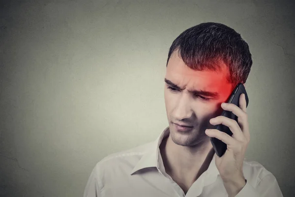 Un homme au téléphone avec des maux de tête. Concept de rayonnement cellulaire mobile — Photo