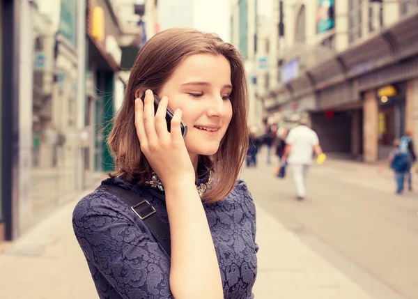 Ei dame som snakker i mobiltelefon mens hun går på gaten om sommeren. – stockfoto