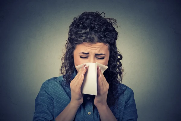 Closeup portrait woman sneezing in a tissue blowing her runny nose Stock Photo