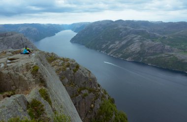 Rogaland, Norveç - 23 Mayıs 2017: Bir çift Norveç 'in Kürsü kayasının bulutlu bir gününde Lysefjord' un güzel manzarasının tadını çıkarıyor. Preikestolen veya Preacher 's kürsüsü de denir..