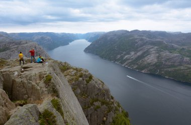 Rogaland, Norveç - 23 Mayıs 2017: Norveç 'in Kürsü kayasının bulutlu bir gününde Lysefjord' un güzel manzarasının tadını çıkaran yürüyüşçüler. Preikestolen veya Preacher 's kürsüsü de denir..