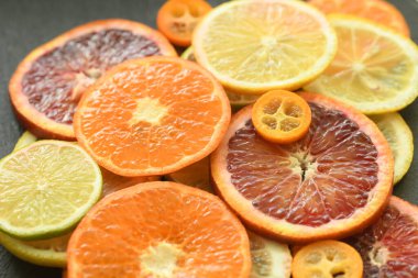 Olgun taze Sicilya kanı portakallı limonlu limonlu kumkuat, koyu yeşil arka plan. Sulu, tatlı, ekşi, narenciye, ince dilimler. Sağlıklı besleyici gıda konsepti, vejetaryen vejetaryen diyeti