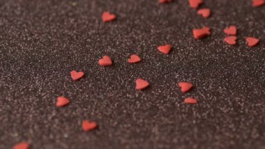 Kırmızı kalp şeklinde şeker konfetileri yalan söylüyor, daha fazla kapak örtüsü dağınık kahverengi yüzey yavaş hareket. Romantik aşk, Sevgililer Günü, Anneler Günü, düğün tasarım konsepti.